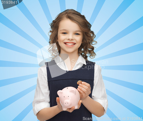 Image of happy girl holding piggy bank and coin