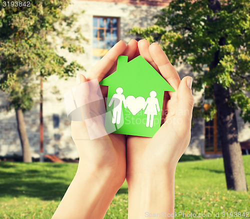 Image of hands holding green house with family