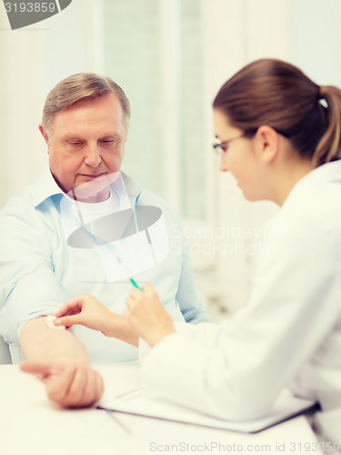 Image of female doctor doing injection to old man