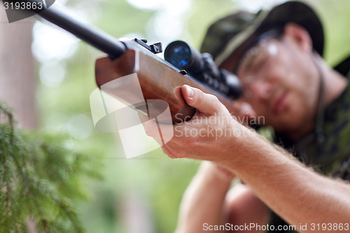 Image of soldier or hunter shooting with gun in forest