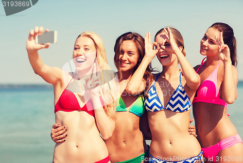 Image of group of smiling women making selfie on beach