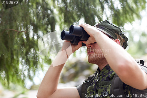 Image of young soldier or hunter with binocular in forest