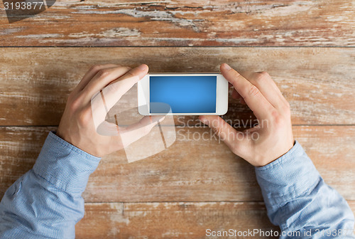 Image of close up of male hands with smartphone on table