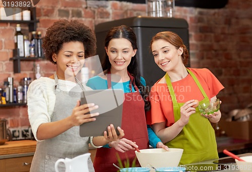 Image of happy women with tablet pc cooking in kitchen