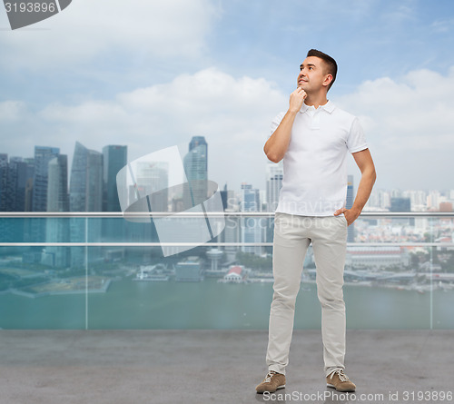 Image of smiling man with hands in pockets looking up