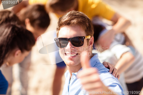 Image of happy young man in sunglasses showing thumbs up