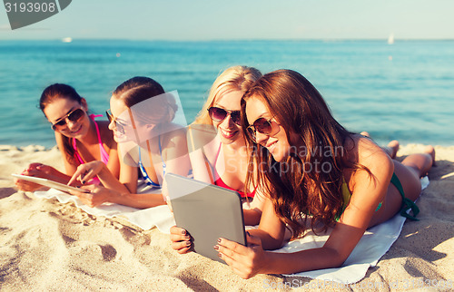 Image of group of smiling young women with tablets on beach