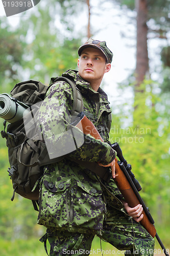 Image of young soldier or hunter with gun in forest