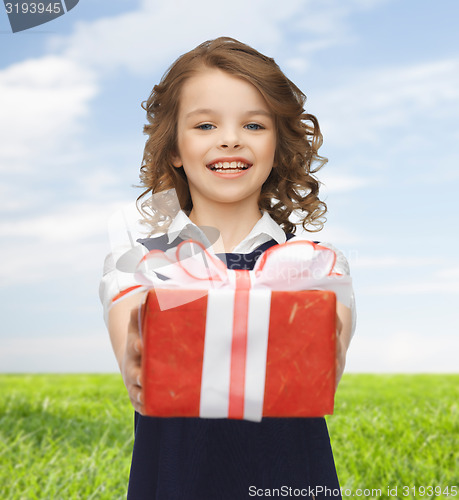 Image of happy girl with red gift box over summer meadow