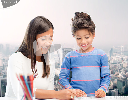 Image of happy mother and daughter drawing with pencils