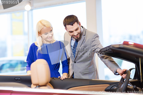 Image of happy couple buying car in auto show or salon