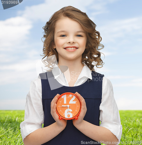 Image of happy girl with alarm clock over summer background