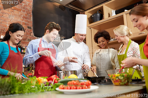 Image of happy friends and chef cook cooking in kitchen