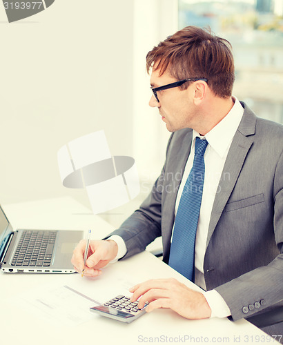 Image of businessman with computer, papers and calculator