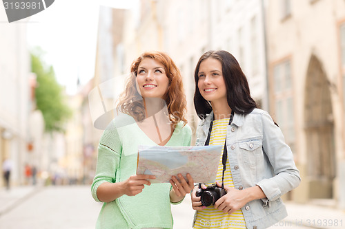 Image of smiling teenage girls with map and camera