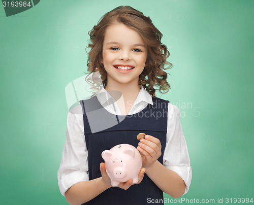 Image of happy girl holding piggy bank and coin