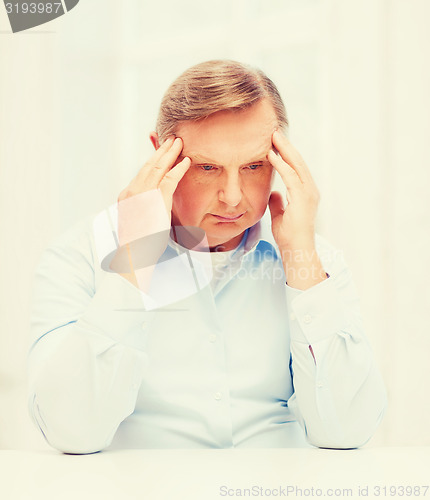 Image of stressed old man holding head at home