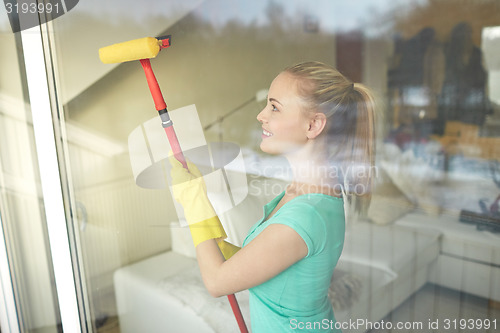 Image of happy woman in gloves cleaning window with sponge