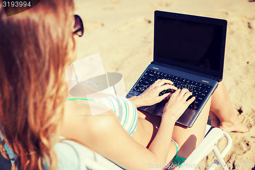 Image of girl looking at laptop on the beach