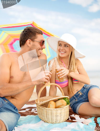 Image of chappy ouple having picnic and sunbathing on beach