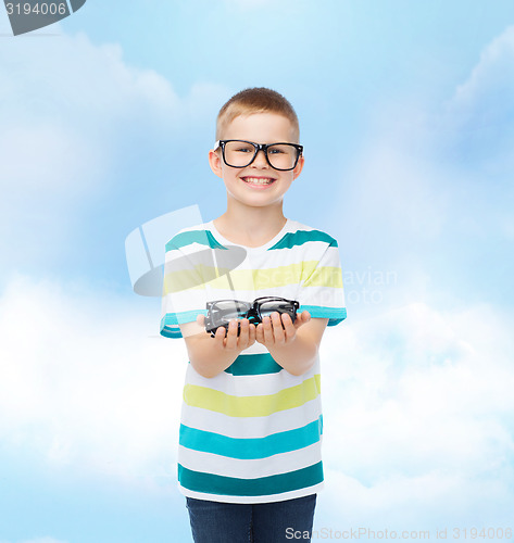 Image of smiling boy in eyeglasses holding spectacles