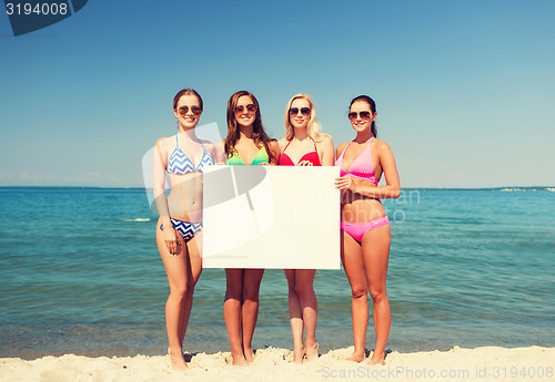 Image of group of smiling women with blank board on beach