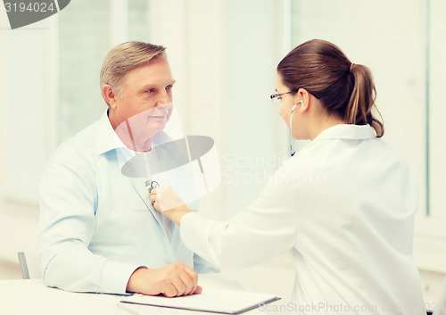 Image of female doctor with old man listening to heart beat