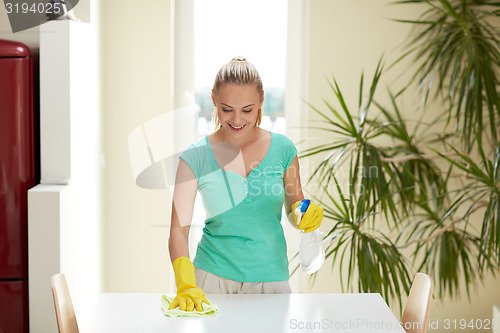 Image of happy woman cleaning table at home kitchen