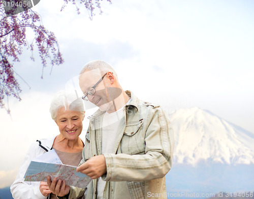 Image of happy senior couple with travel map over mountains