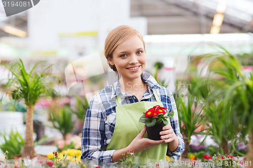 Image of happy woman holding flowers in greenhouse