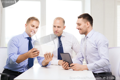Image of three smiling businessmen with tablet pc in office