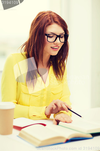 Image of smiling student girl reading books in library