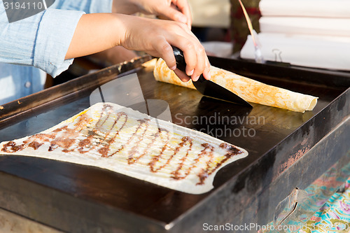 Image of close up of cook frying pancakes at street market