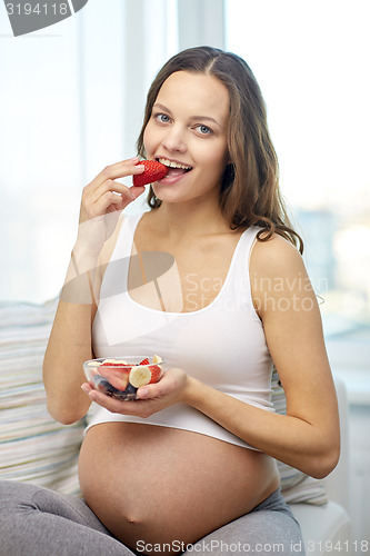 Image of happy pregnant woman eating fruits at home