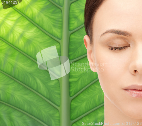 Image of young woman face over green leaf background