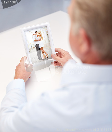 Image of close up of old man holding young couple photo
