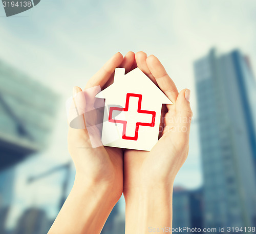 Image of hands holding paper house with red cross