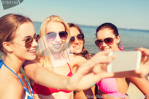 Image of group of smiling women making selfie on beach