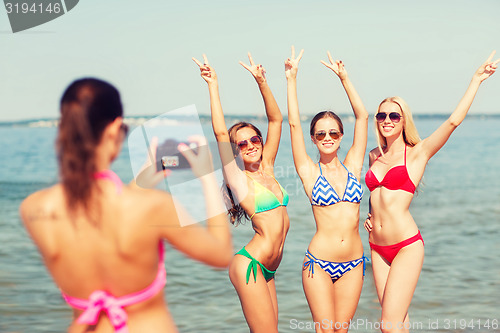 Image of group of smiling women photographing on beach