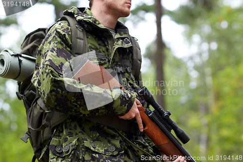Image of close up of soldier or hunter with gun in forest