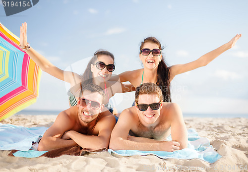 Image of group of happy friends having fun on beach