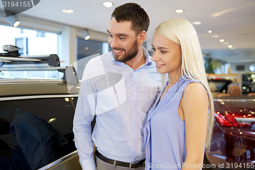 Image of happy couple buying car in auto show or salon