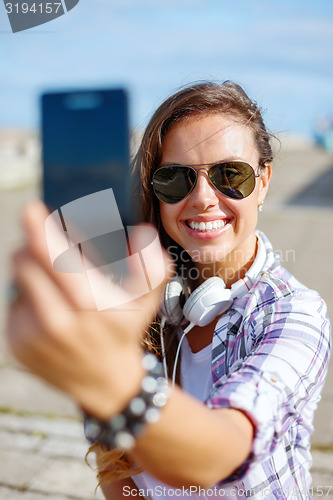 Image of smiling teenager taking picture with smartphone