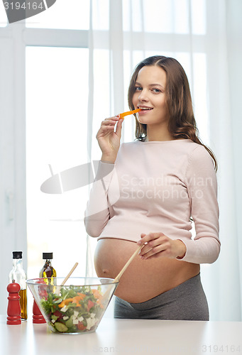 Image of happy pregnant woman preparing food at home