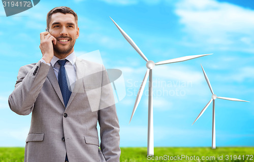 Image of smiling businessman with smartphone outdoors