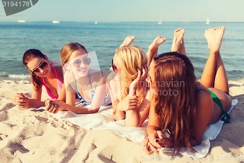 Image of group of smiling women in sunglasses on beach