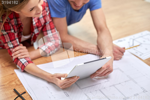 Image of close up of couple with tablet pc and blueprint