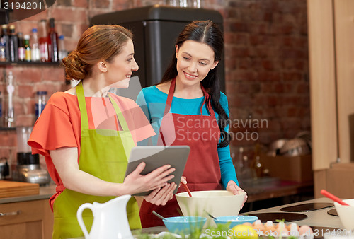 Image of happy women with tablet pc cooking in kitchen