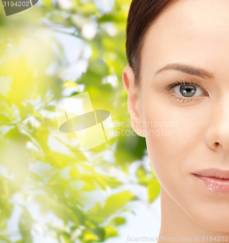 Image of young woman face over green leaves background