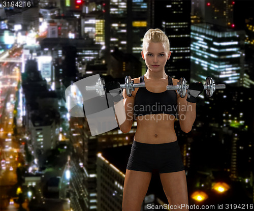 Image of sporty woman with heavy steel dumbbells